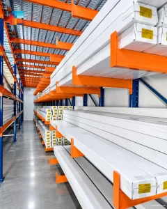 Cantilever racking system with orange arms storing long materials in an industrial warehouse